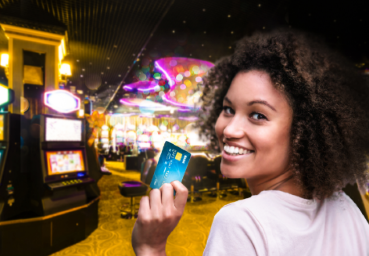 Person in Casino holding a credit card up and smiling